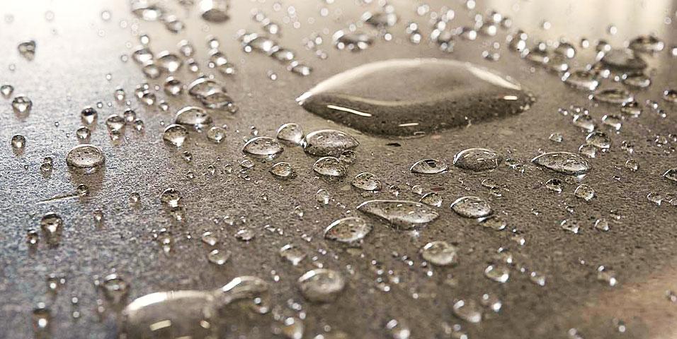 Waterdruppels parelen af op een geïmpregneerde betonvloer